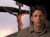Man in front of an image depicting the crucifixion of Jesus.